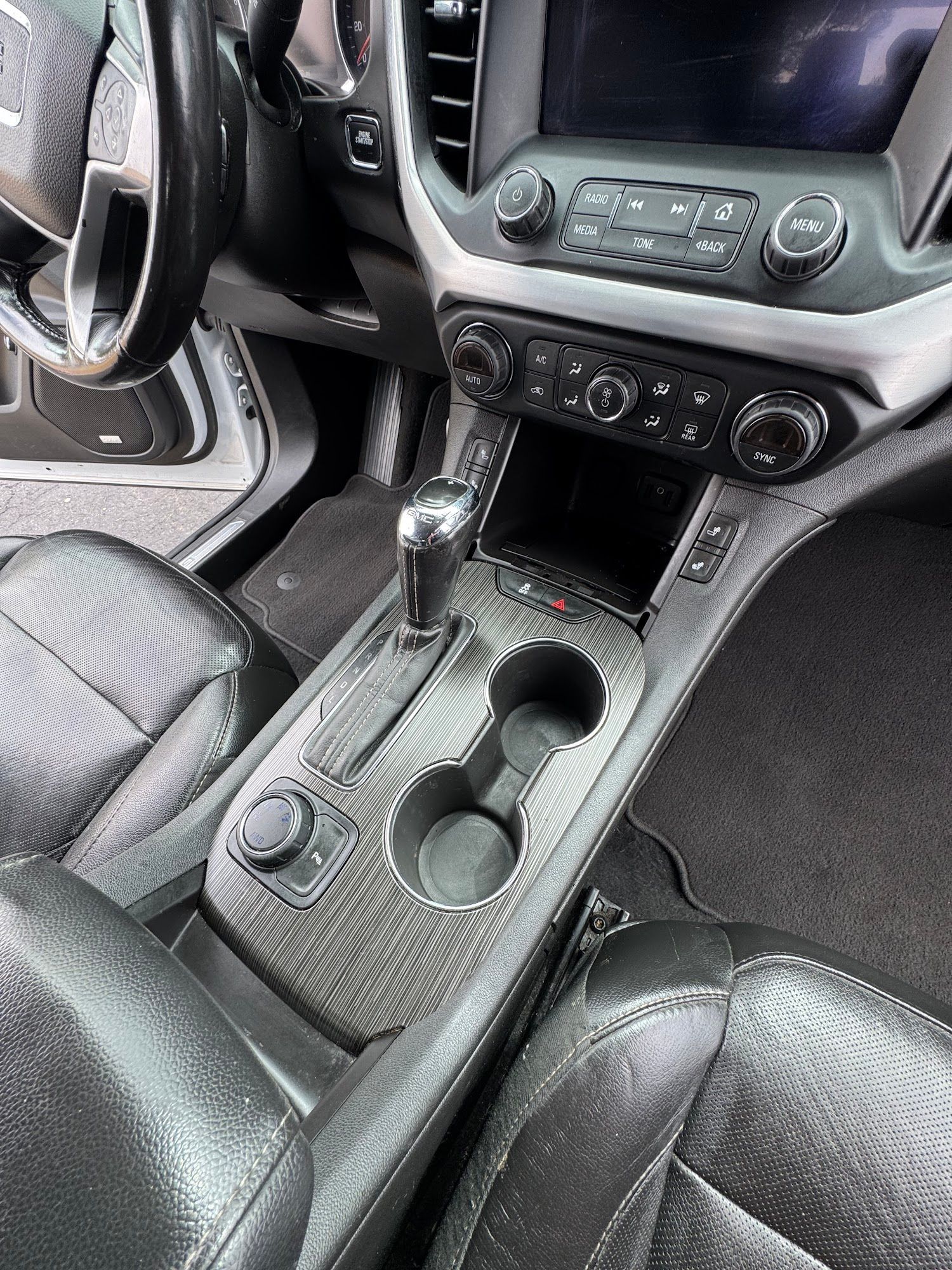 Interior car shot with black seats, console, and dashboard; cup holders and gear shift visible.