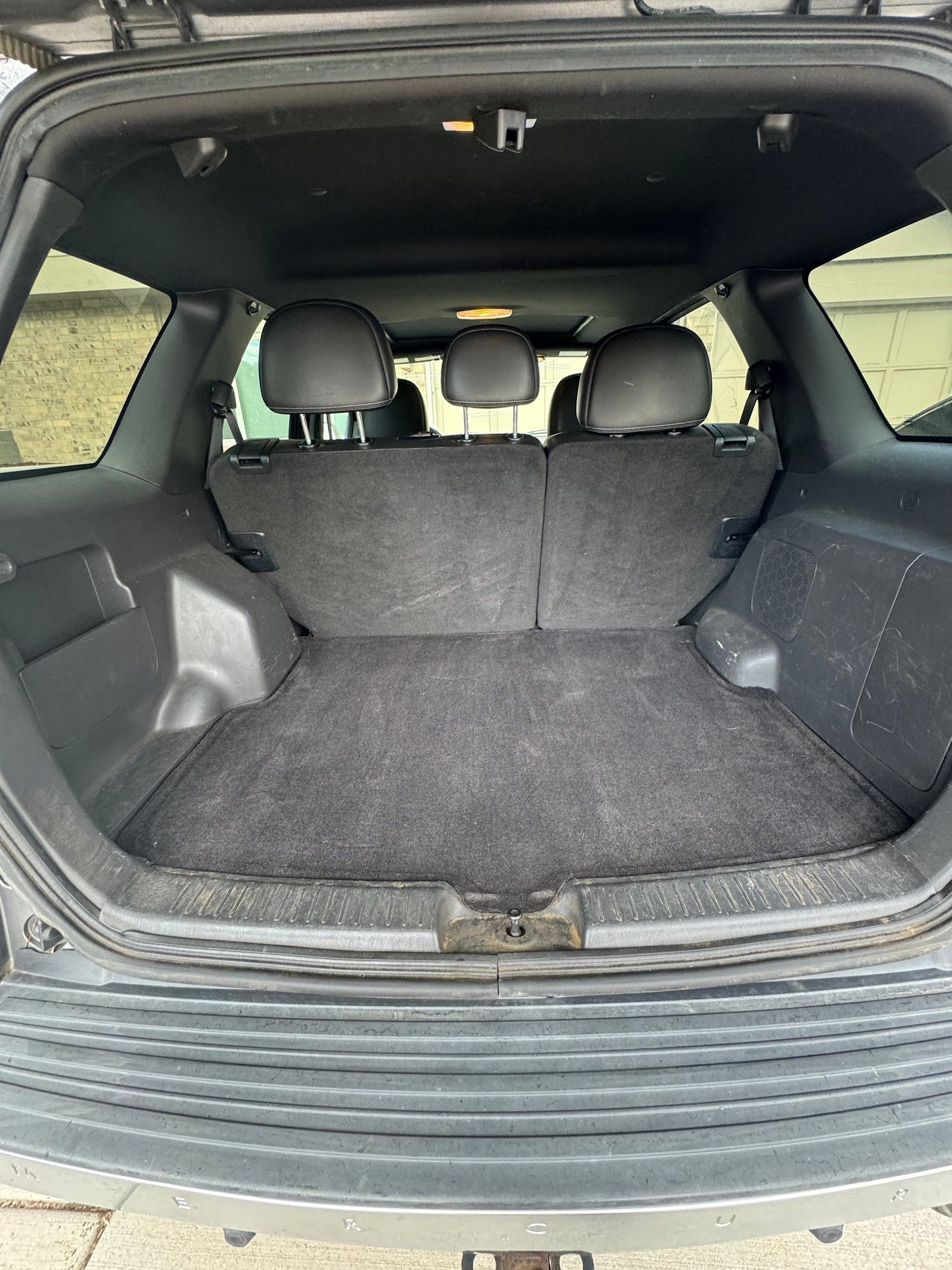 Empty car trunk with black carpet and rear seats visible.