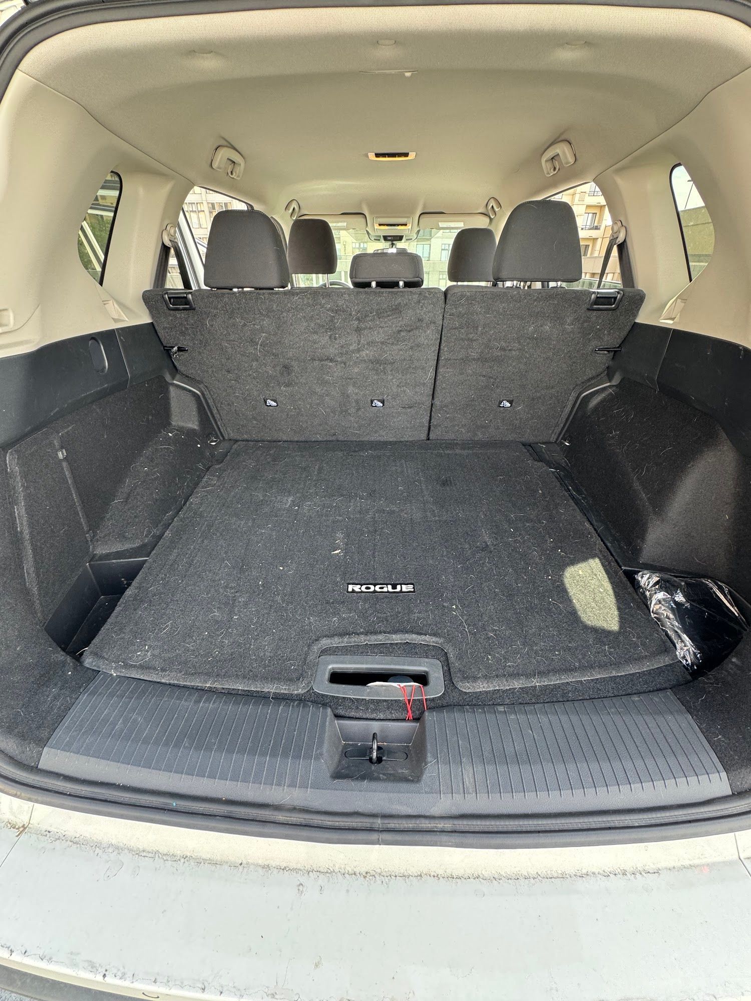 Empty car trunk interior; gray carpet and seats; dark floor cover, cargo space.