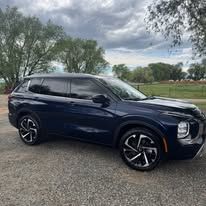 Dark blue SUV parked on a gravel surface. Cloudy sky and trees in the background.