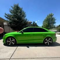 Bright green car with black wheels parked outside on a sunny day.
