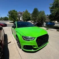 Bright green Audi car parked on a paved road, sunny day.