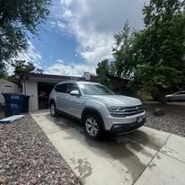 Silver SUV parked in front of a house. Blue sky with white clouds in the background.
