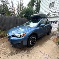 Blue Subaru with a black rooftop carrier parked outdoors.