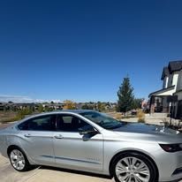Silver Chevrolet Impala parked in front of a house on a sunny day.