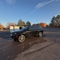 Black SUV parked on a paved lot on a sunny day.