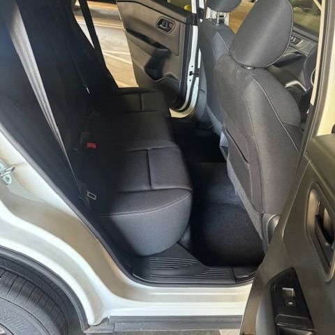 Black car interior with back seats visible. White car door and tire visible.
