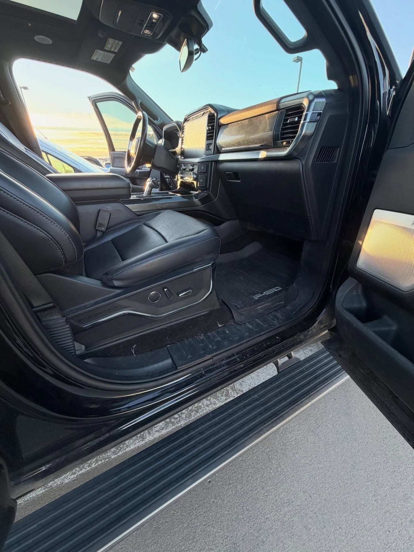 Black truck interior with leather seats, open door.