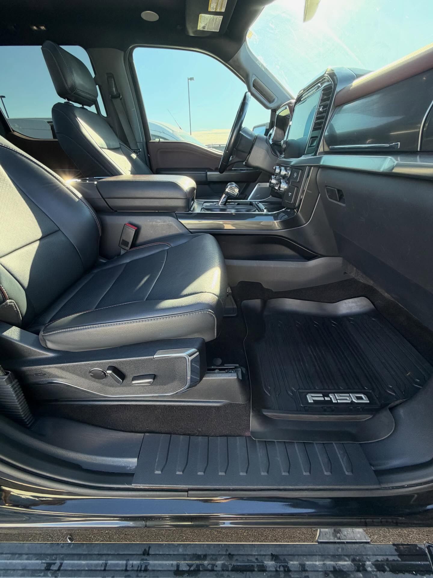 Interior of a black Ford F-150 truck with black leather seats, a dark dashboard, and a floor mat.