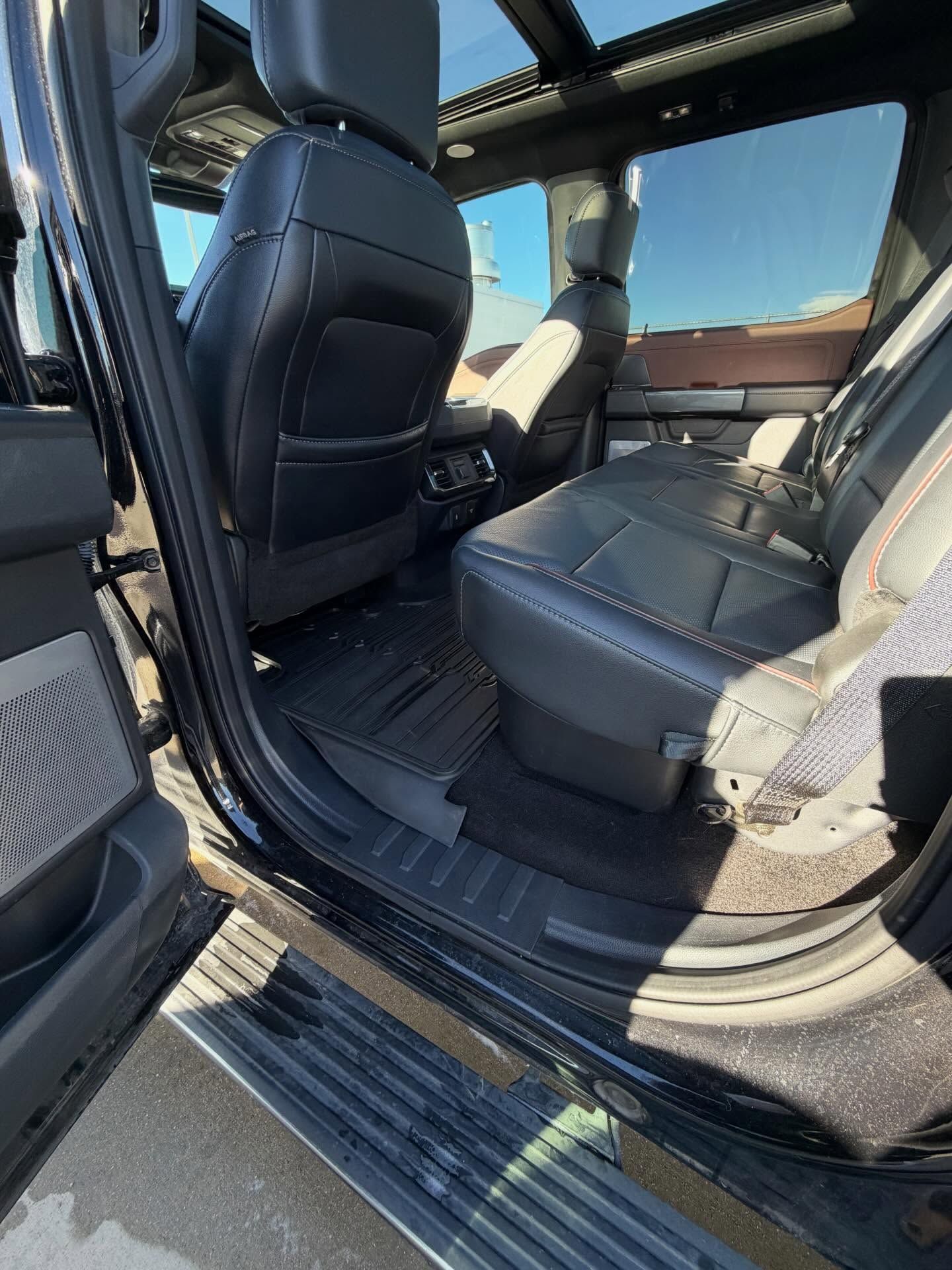 Interior of a black truck.  Leather seats, floor mats, and a sunroof are visible.