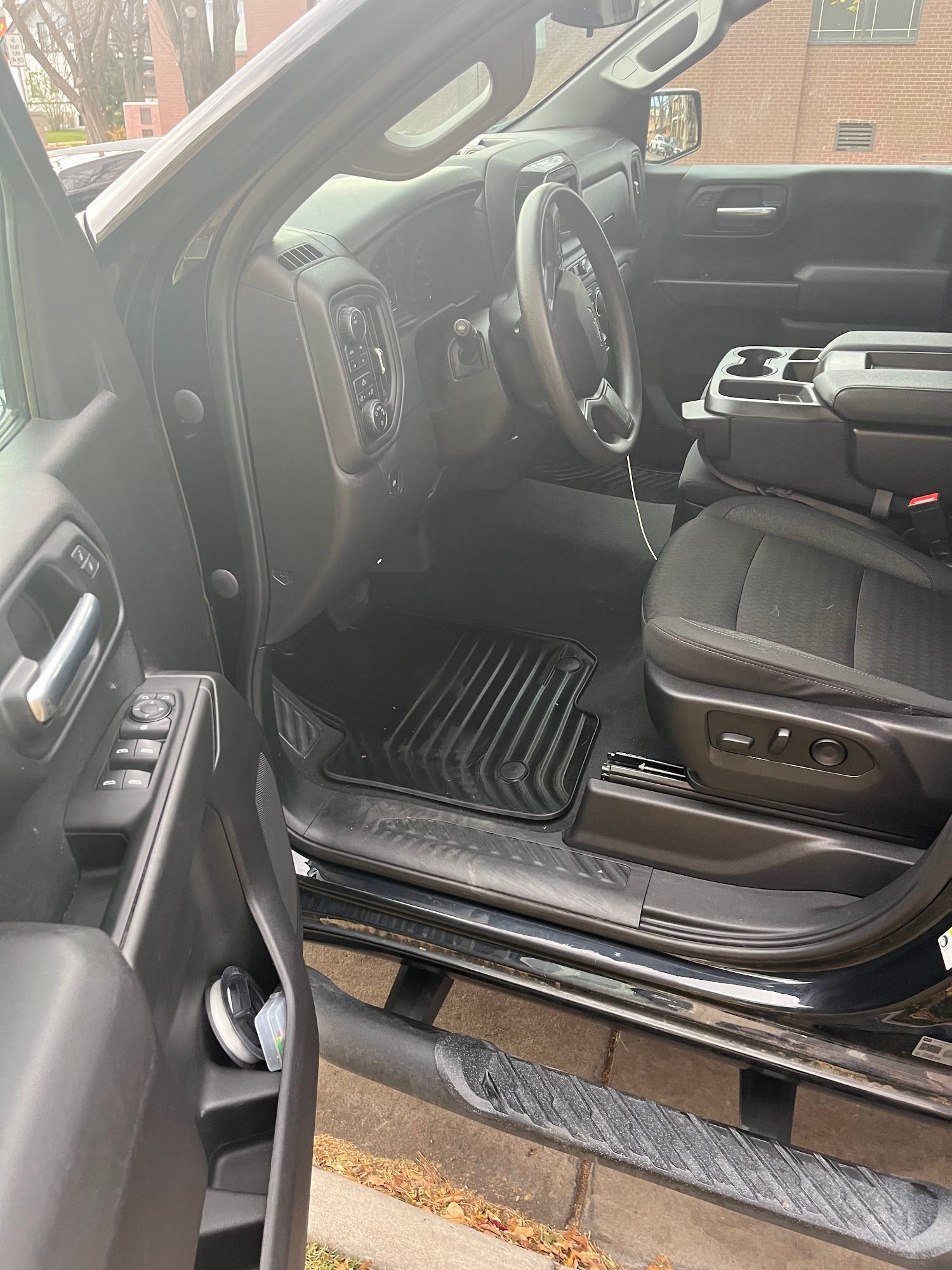 Black truck interior with open door, showing seats, steering wheel, and floor mats.