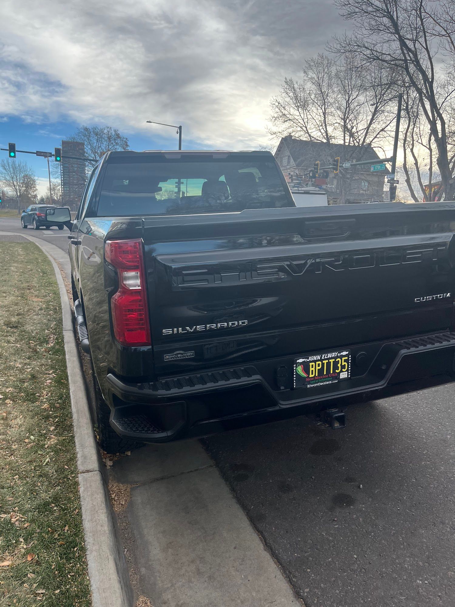 Black pickup truck parked on the side of a road, with a license plate visible.