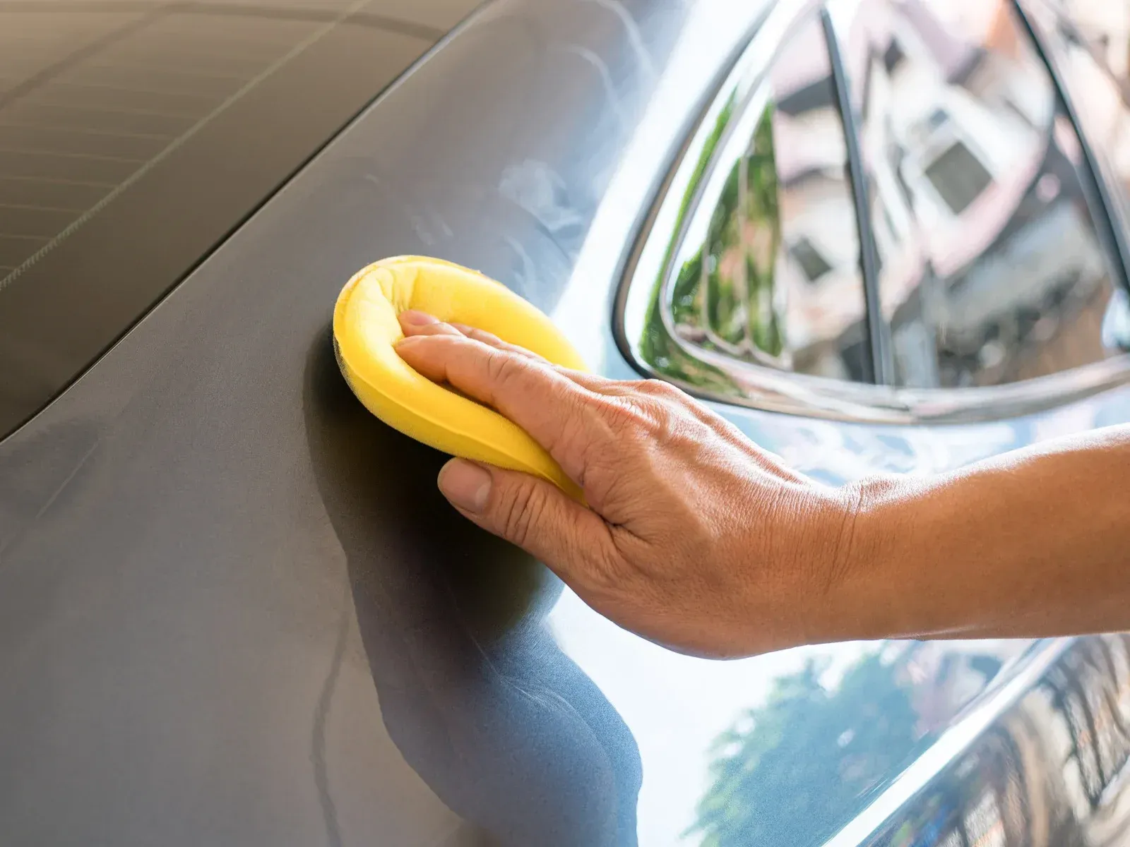 Black car being washed, covered in soap suds, in a garage.