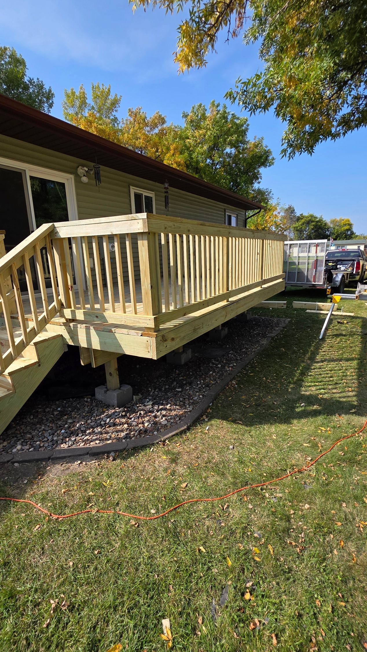 Wooden deck attached to a house with railing and steps on a sunny day.