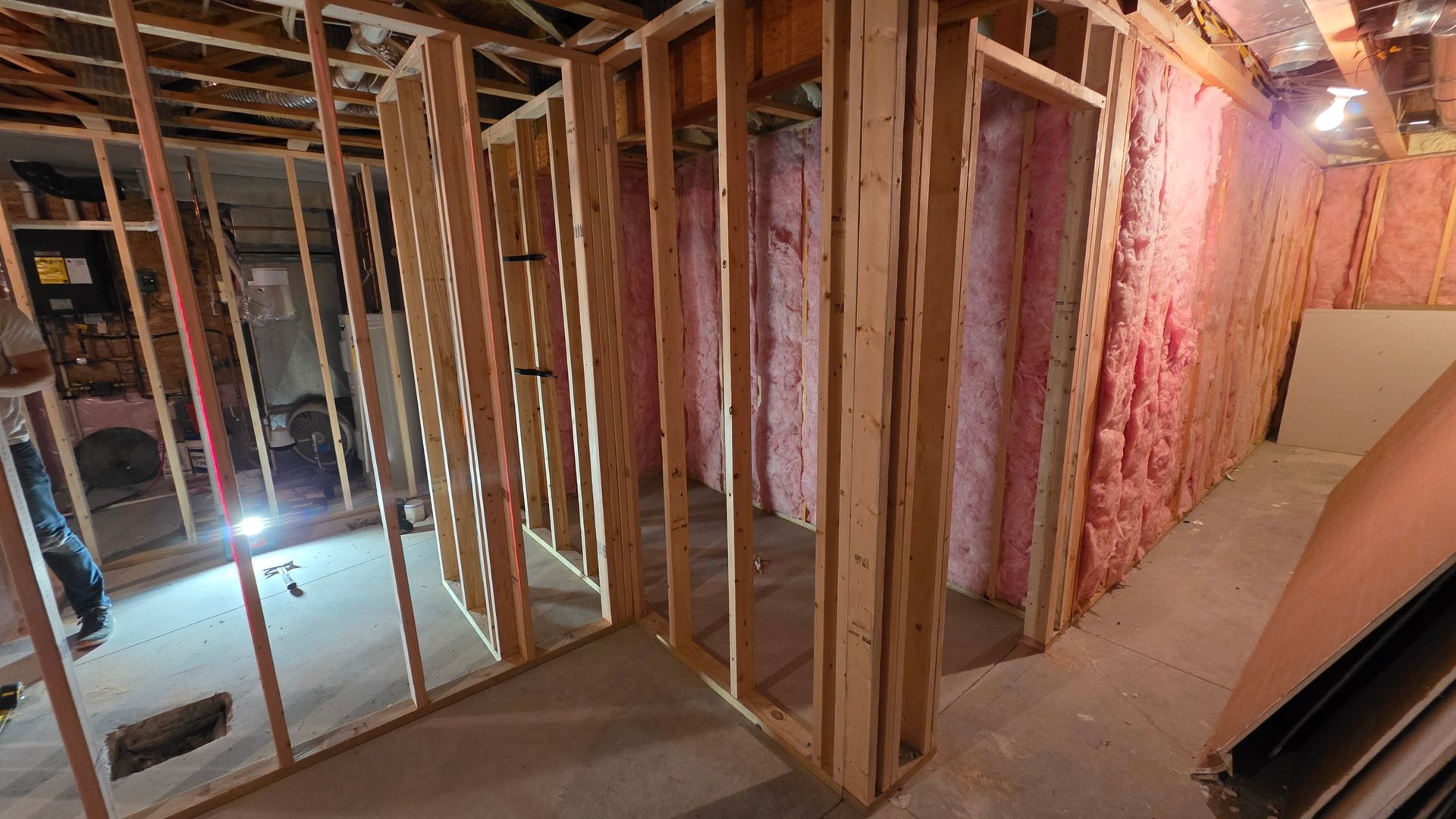 Framing of a room with exposed insulation. Wooden studs form walls and doorways.