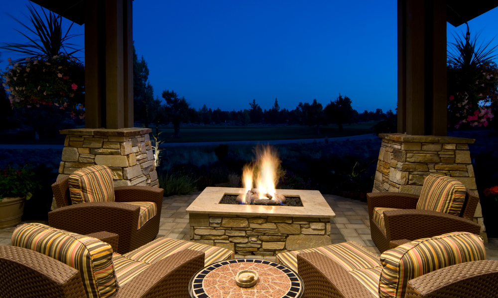 A patio with a fire pit and a couch in front of a house