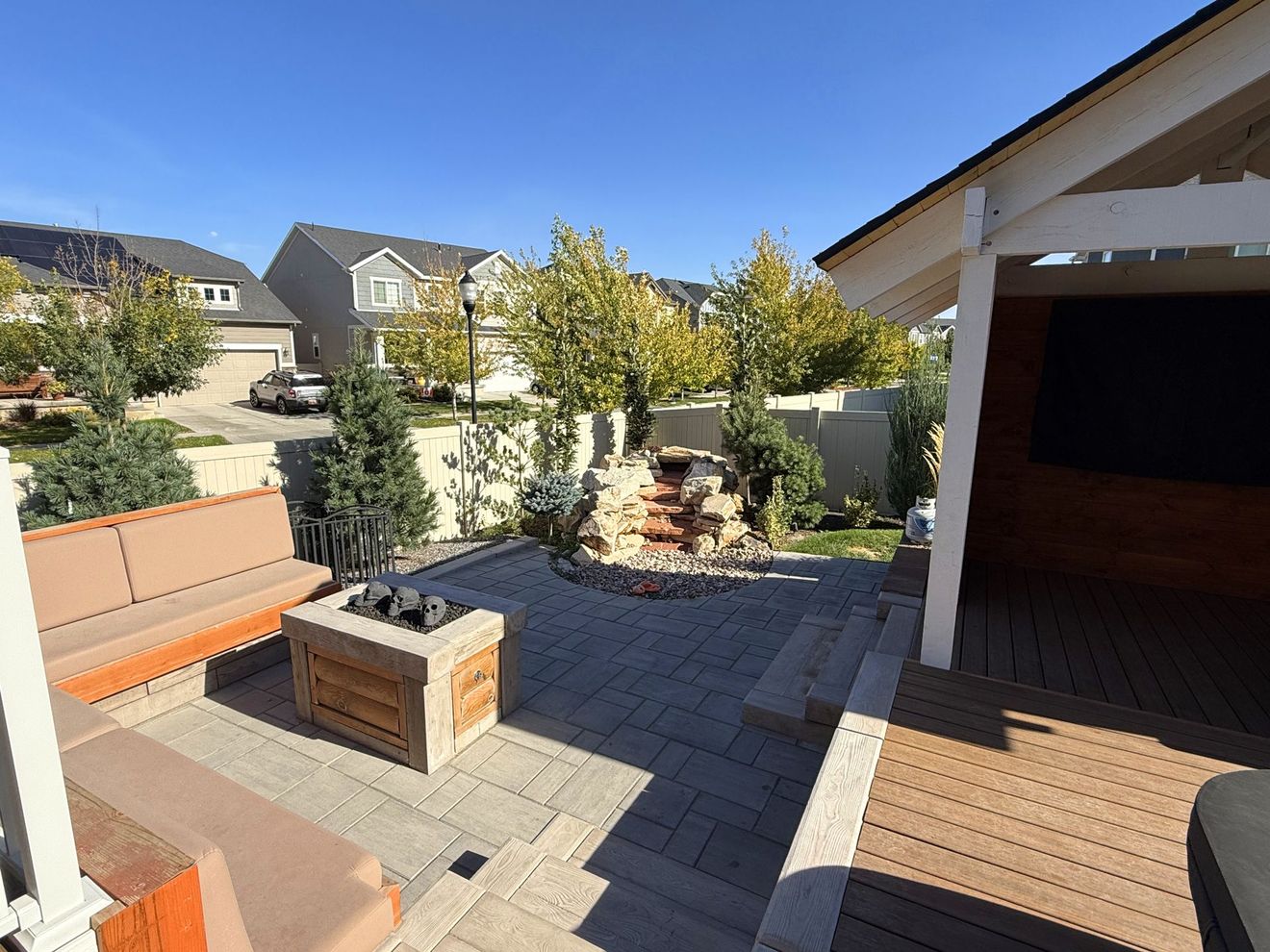 A patio with a fire pit , couch , table and television.