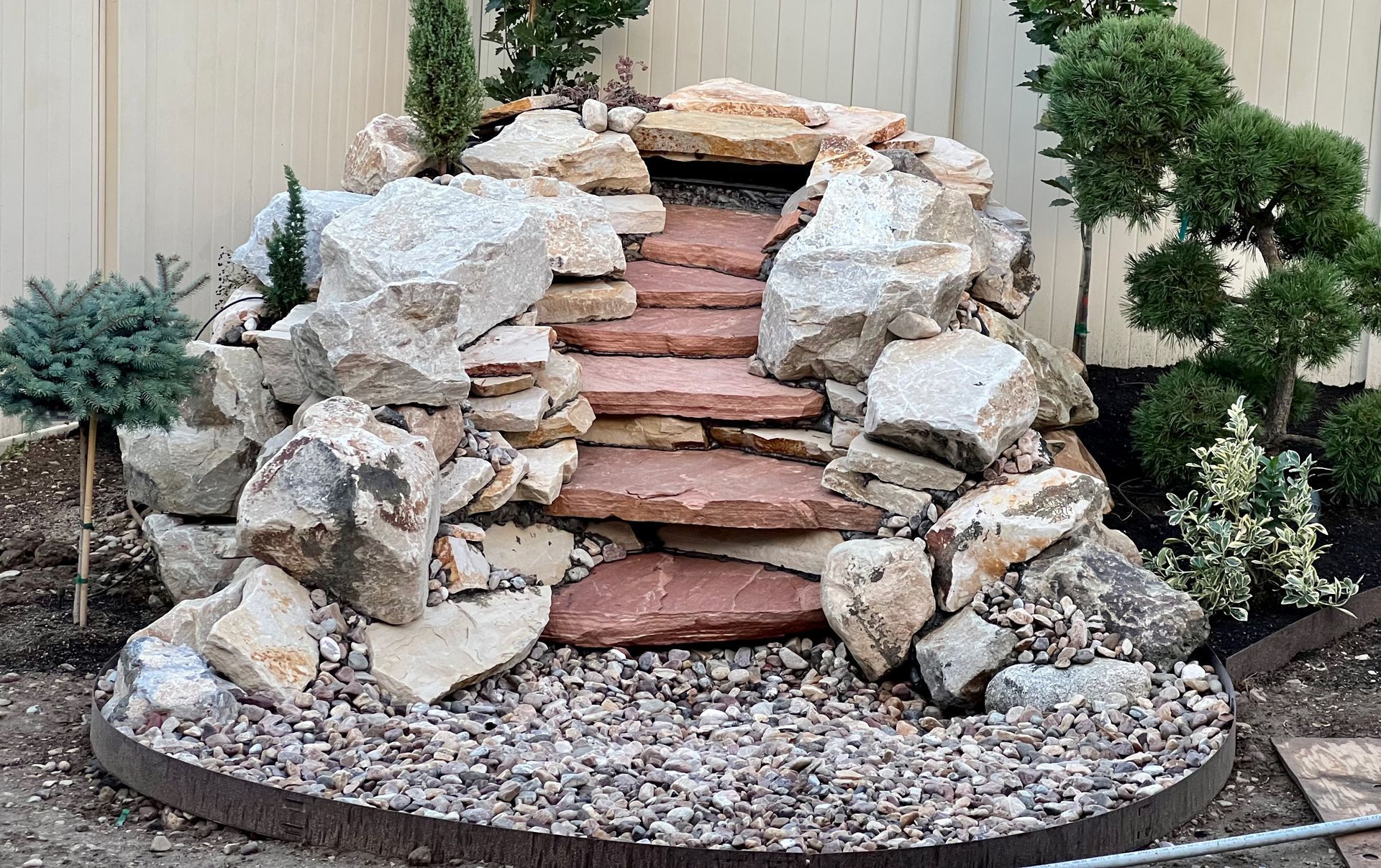 A waterfall made of rocks and steps in a backyard.