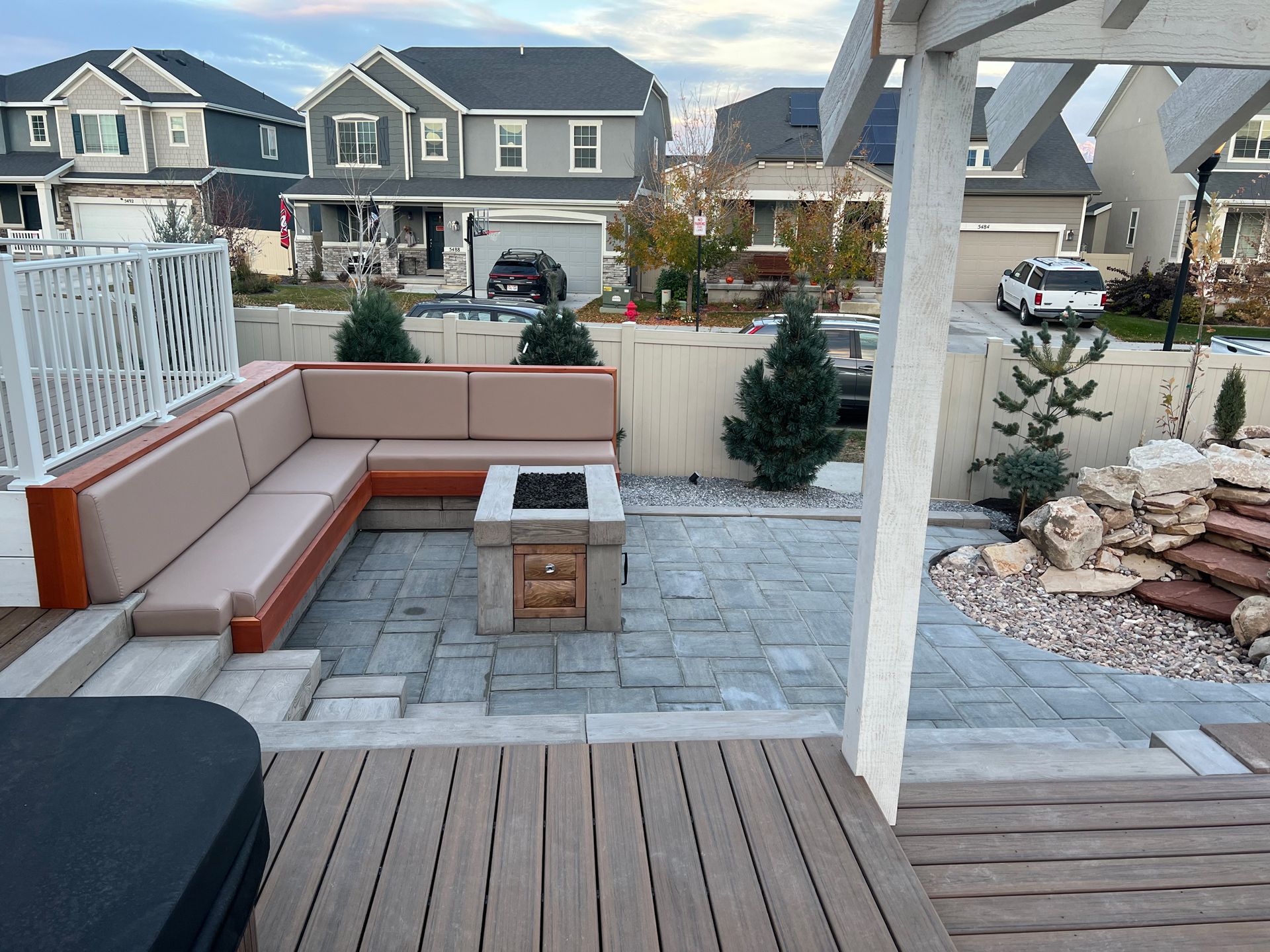 A patio with a fire pit and a couch under a pergola.