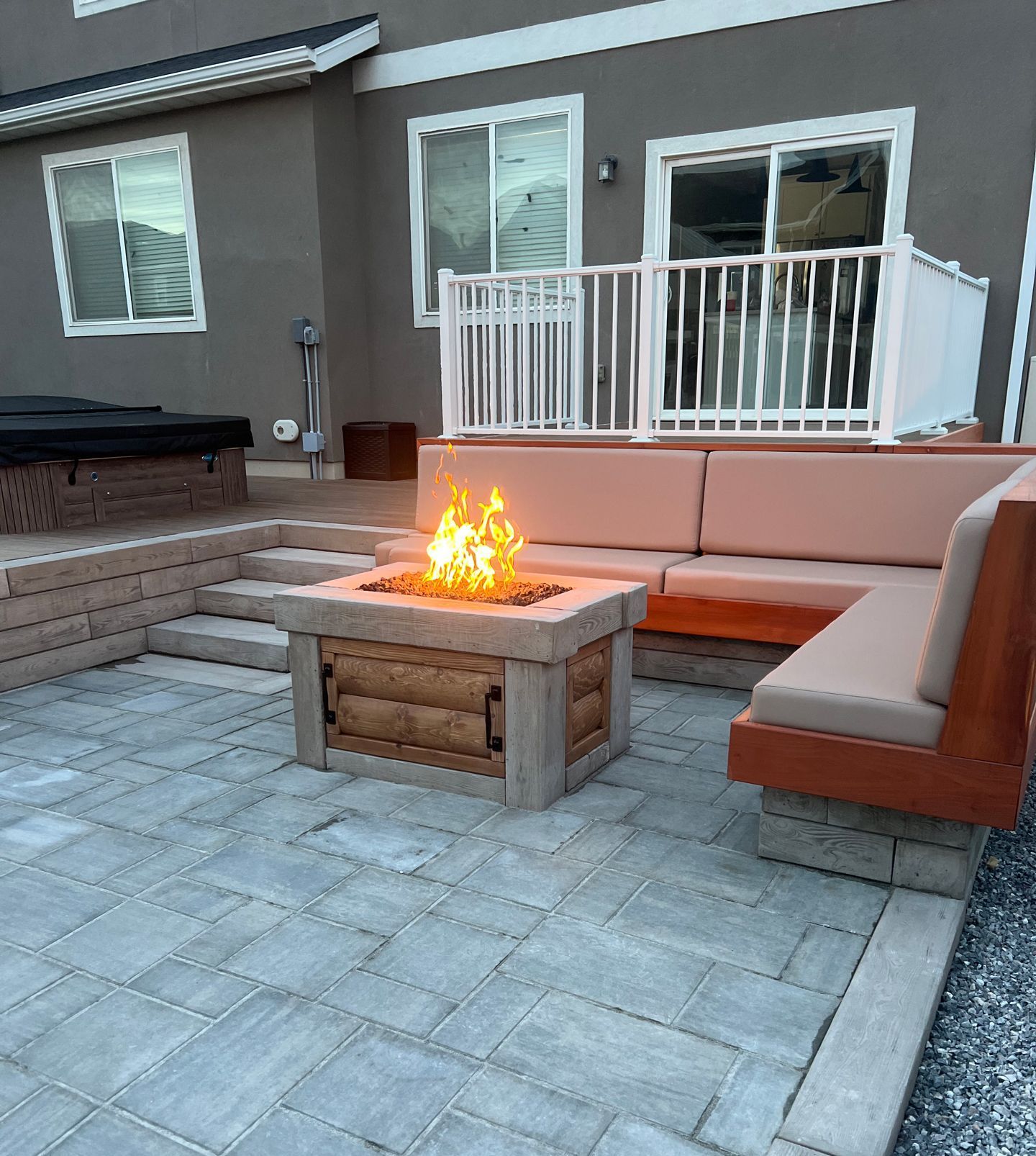 A patio with a fire pit and a couch in front of a house