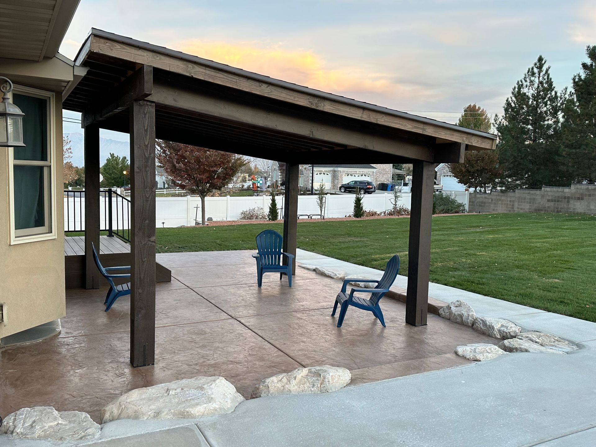A patio with chairs under a covered patio in front of a house.