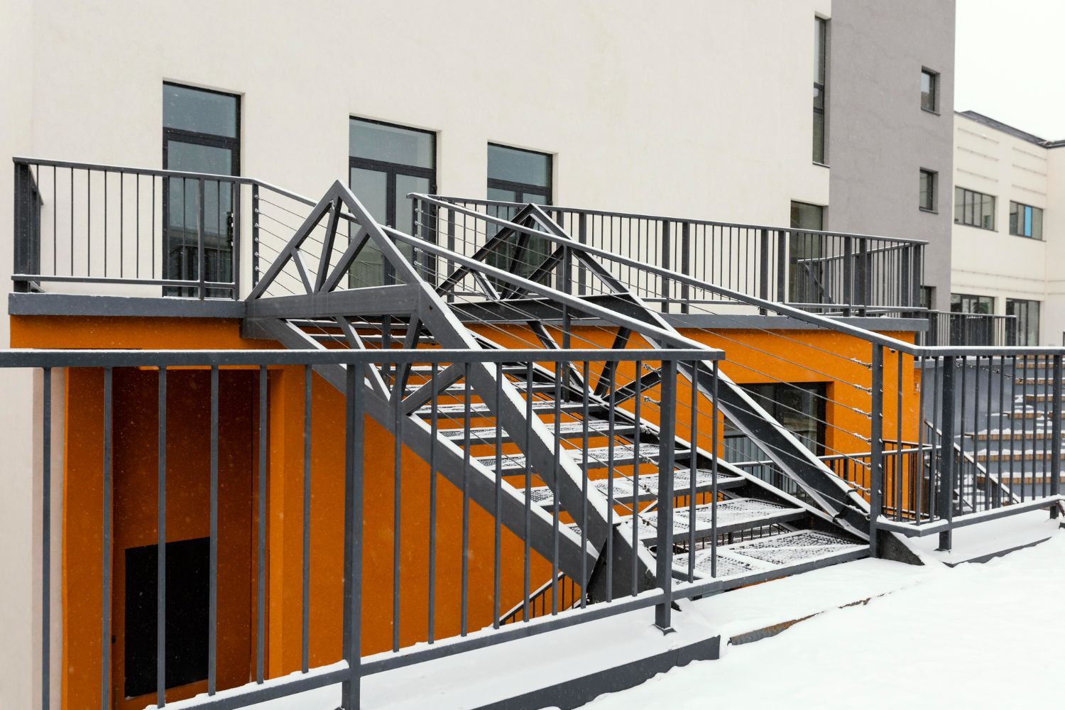 Exterior metal staircase with railings, covered in snow, next to a building  in State College