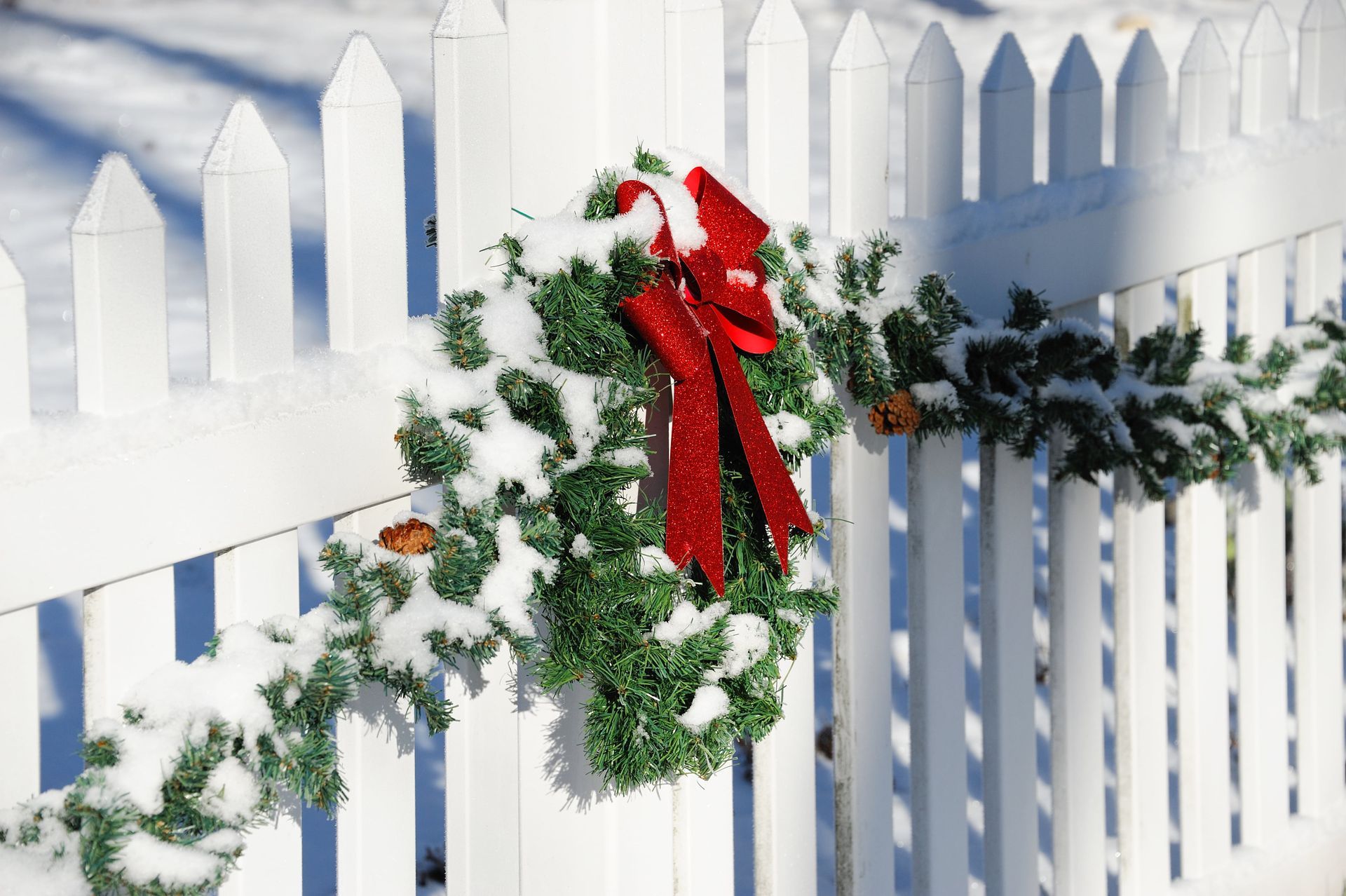 White picket fence with snowy garland and a red bow in State College.