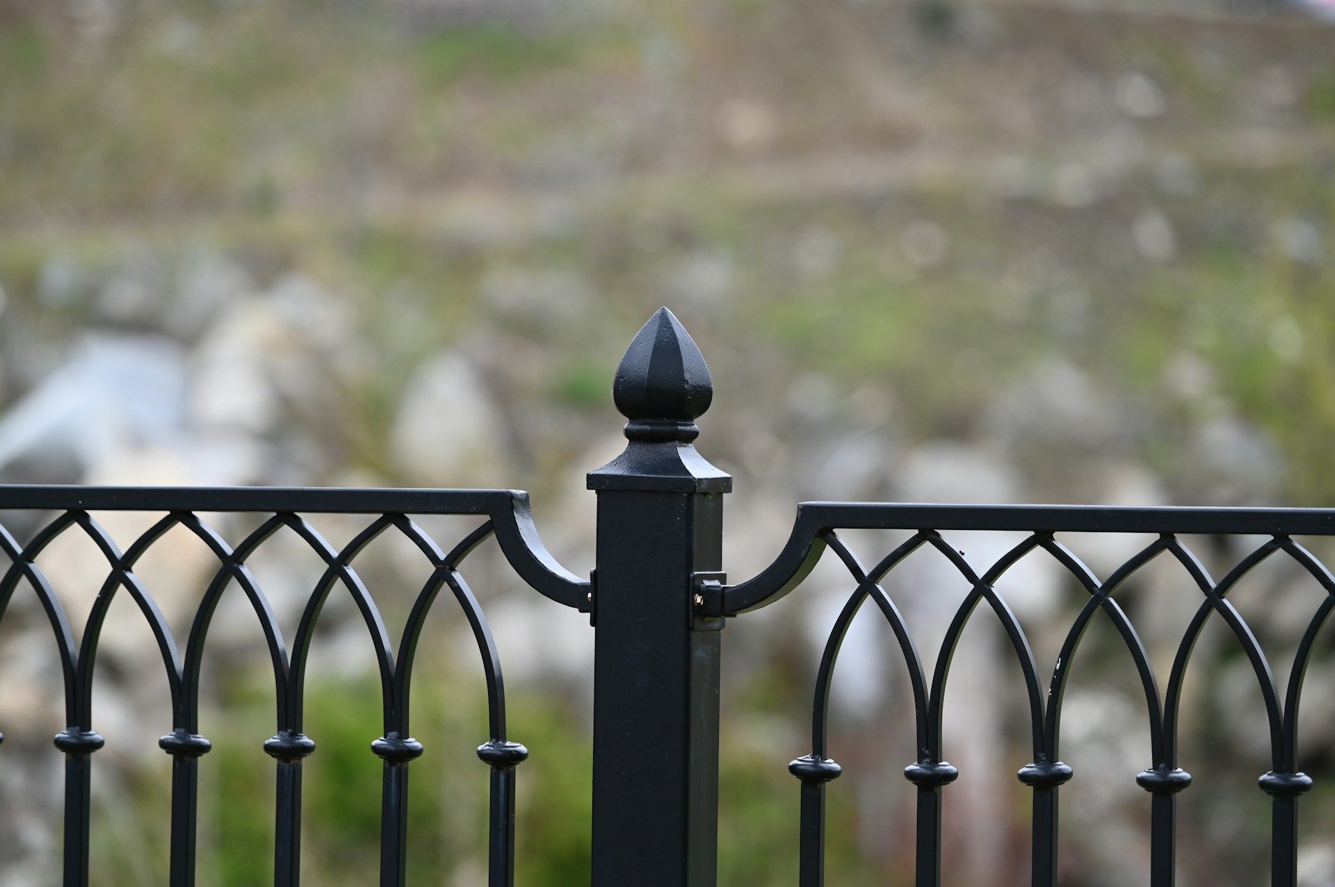 Black wrought iron fence with decorative arched design, topped with a finial in State College.