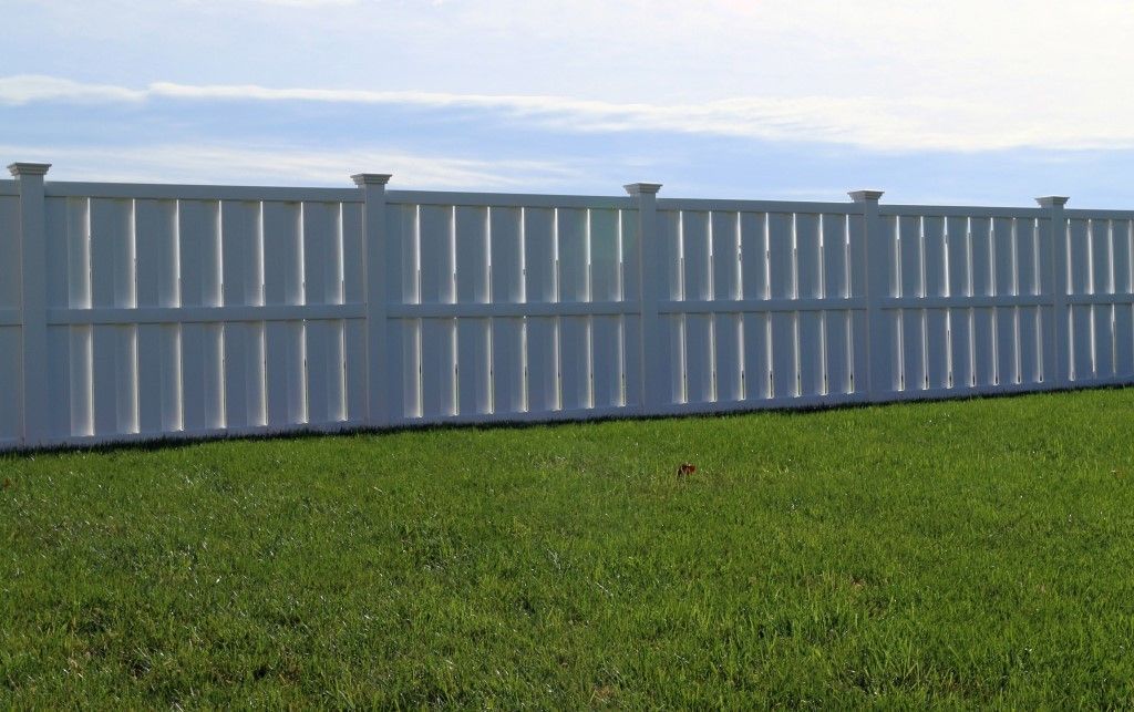 White fence and gate beside a brick apartment building under a cloudy sky