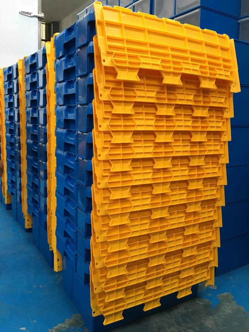 Palets de plástico azules y amarillos apilados uno encima del otro