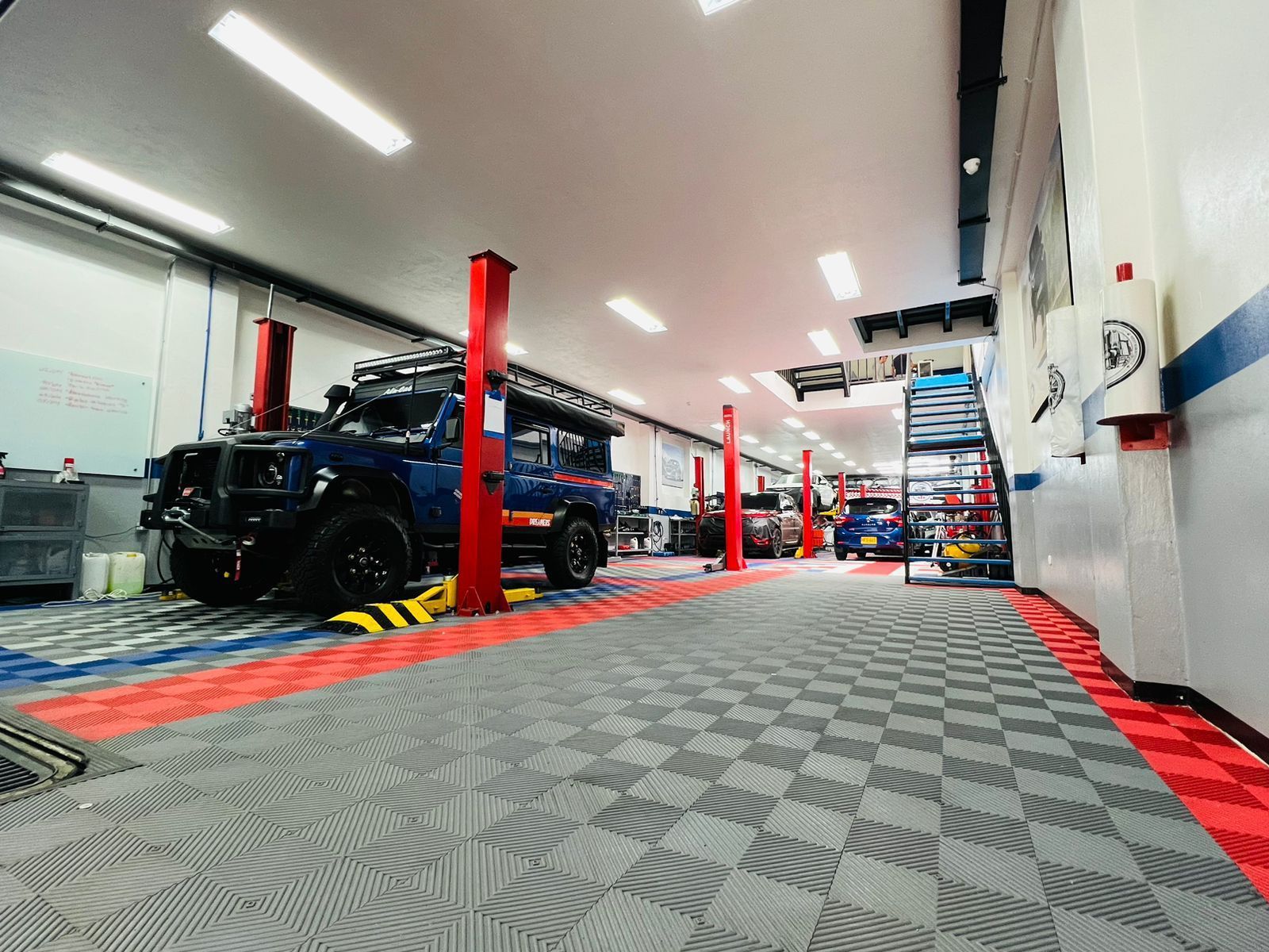 Un jeep azul está estacionado en un elevador en un garaje.