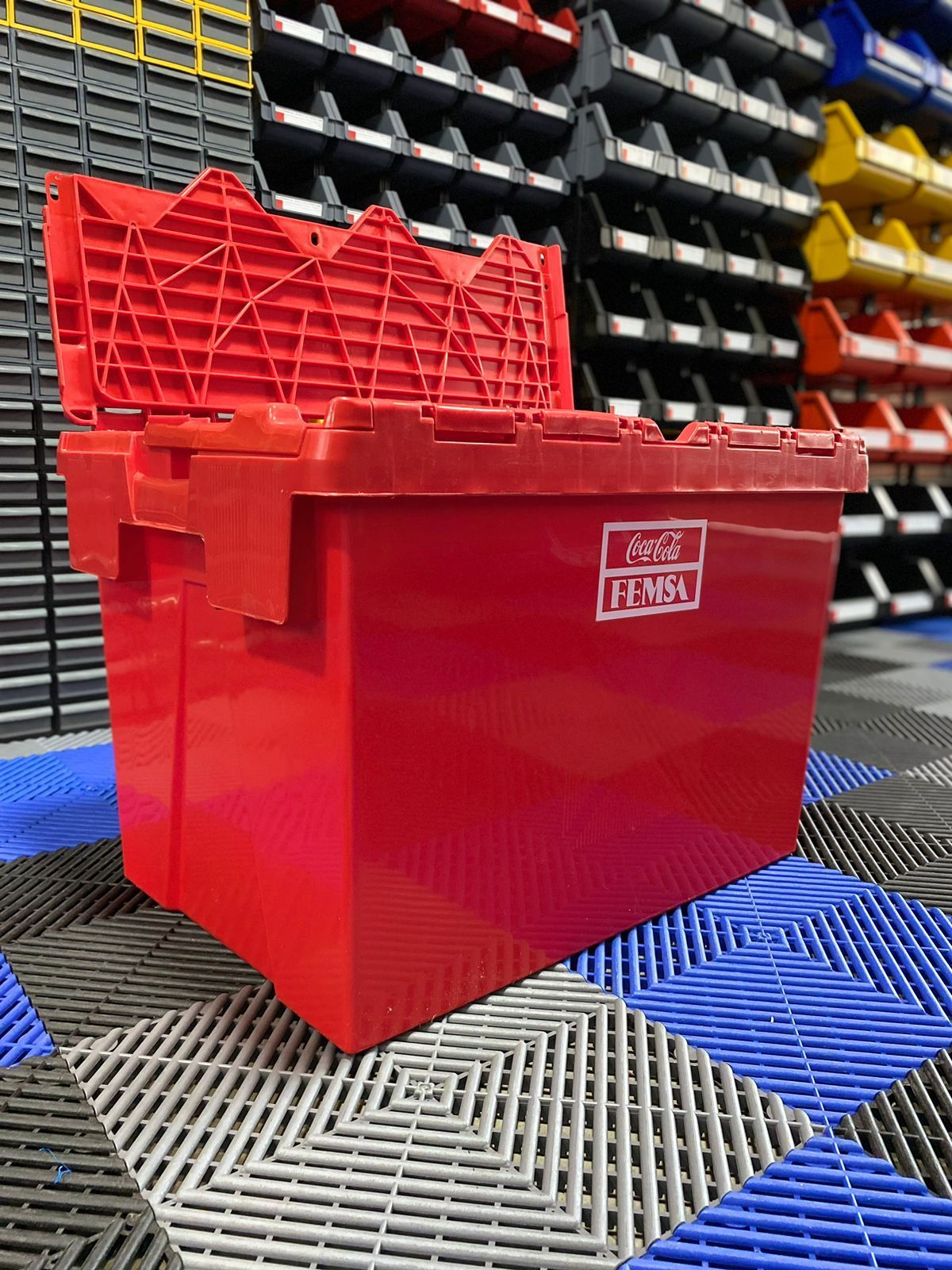 Un recipiente de plástico rojo con tapa se encuentra sobre un suelo de baldosas.