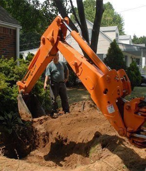 A man is standing next to a large orange excavator