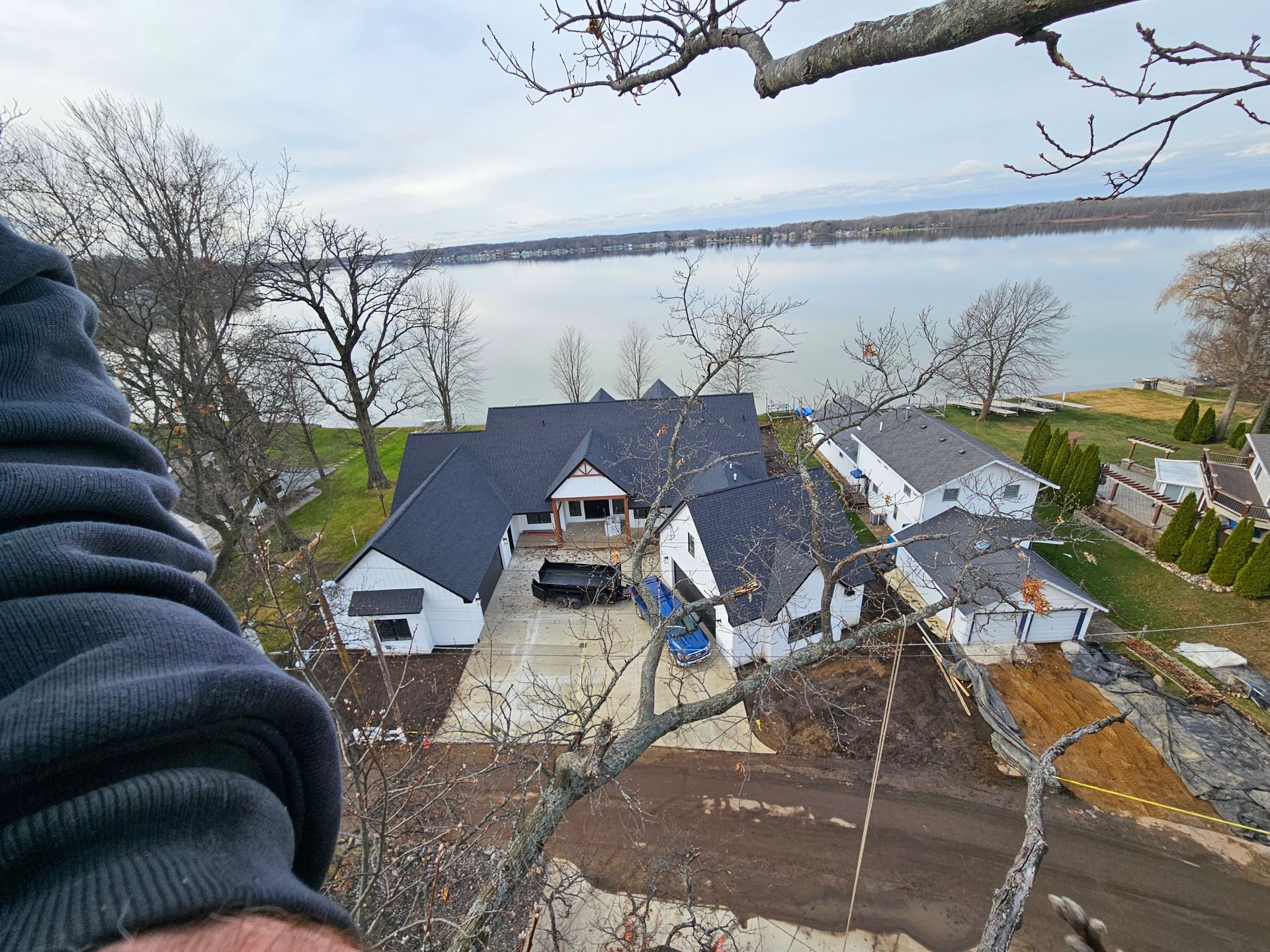 A man is looking down at a house from a tree.