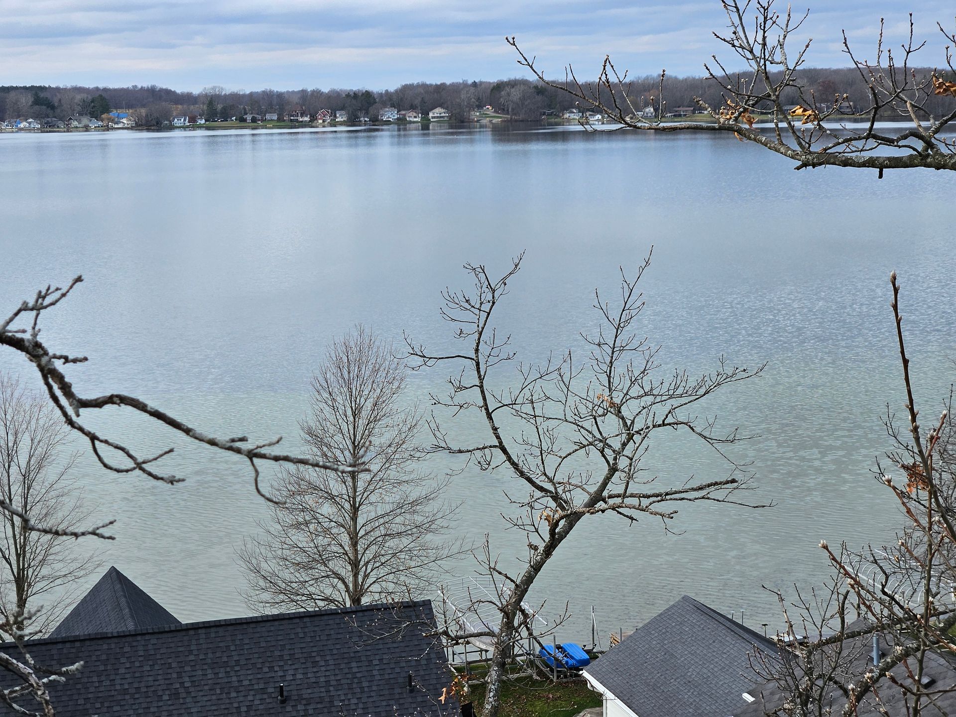 A view of a lake from a house with trees in the foreground