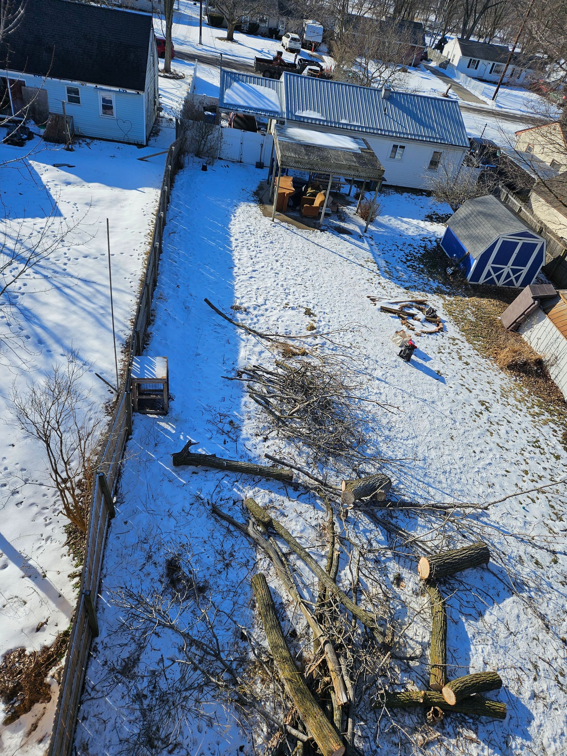 An aerial view of a snowy yard with a house in the background.