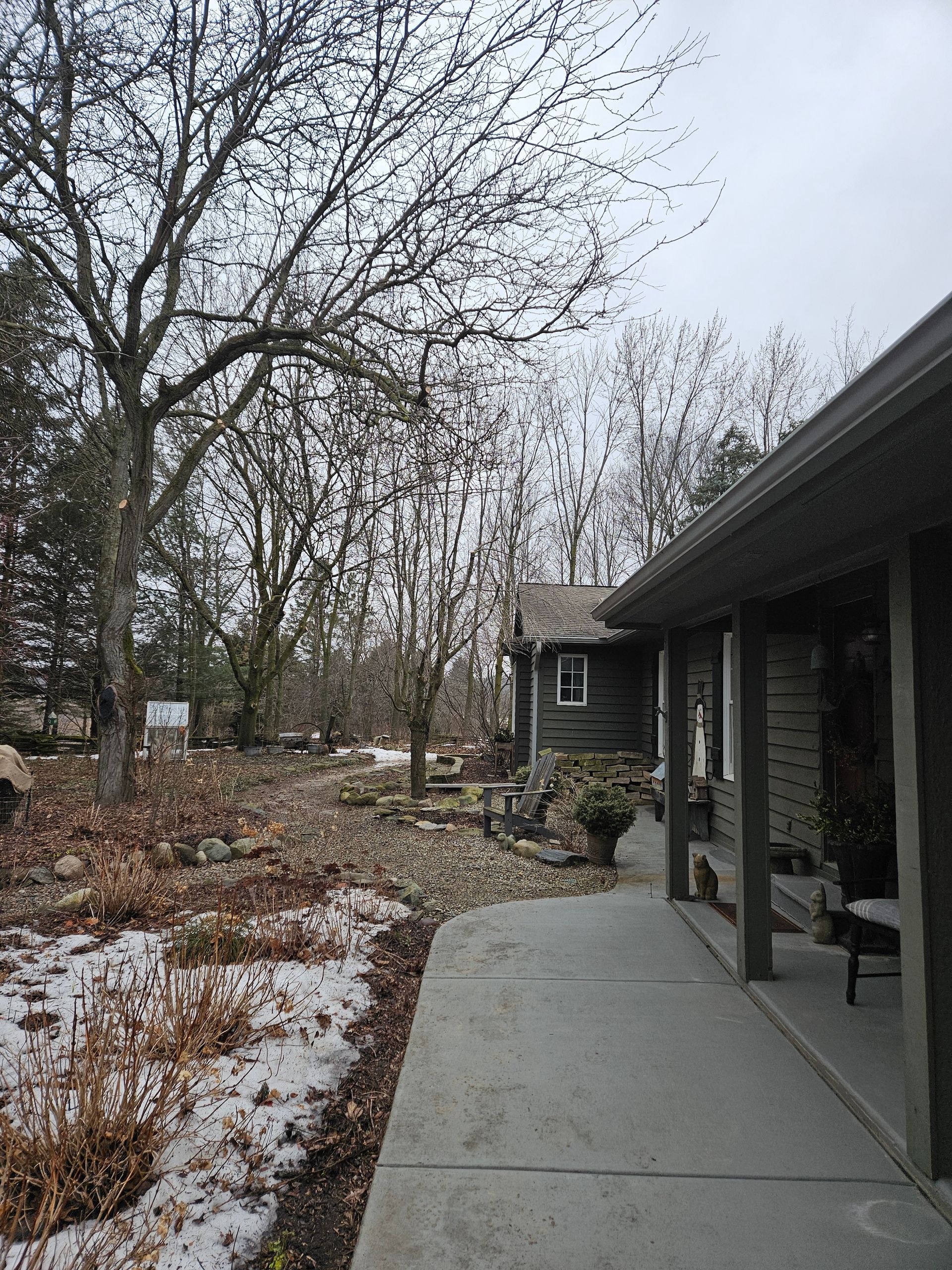 A house with a porch and trees in front of it.