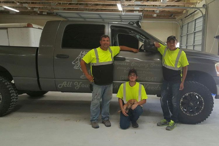 Three men are posing for a picture in front of a truck.