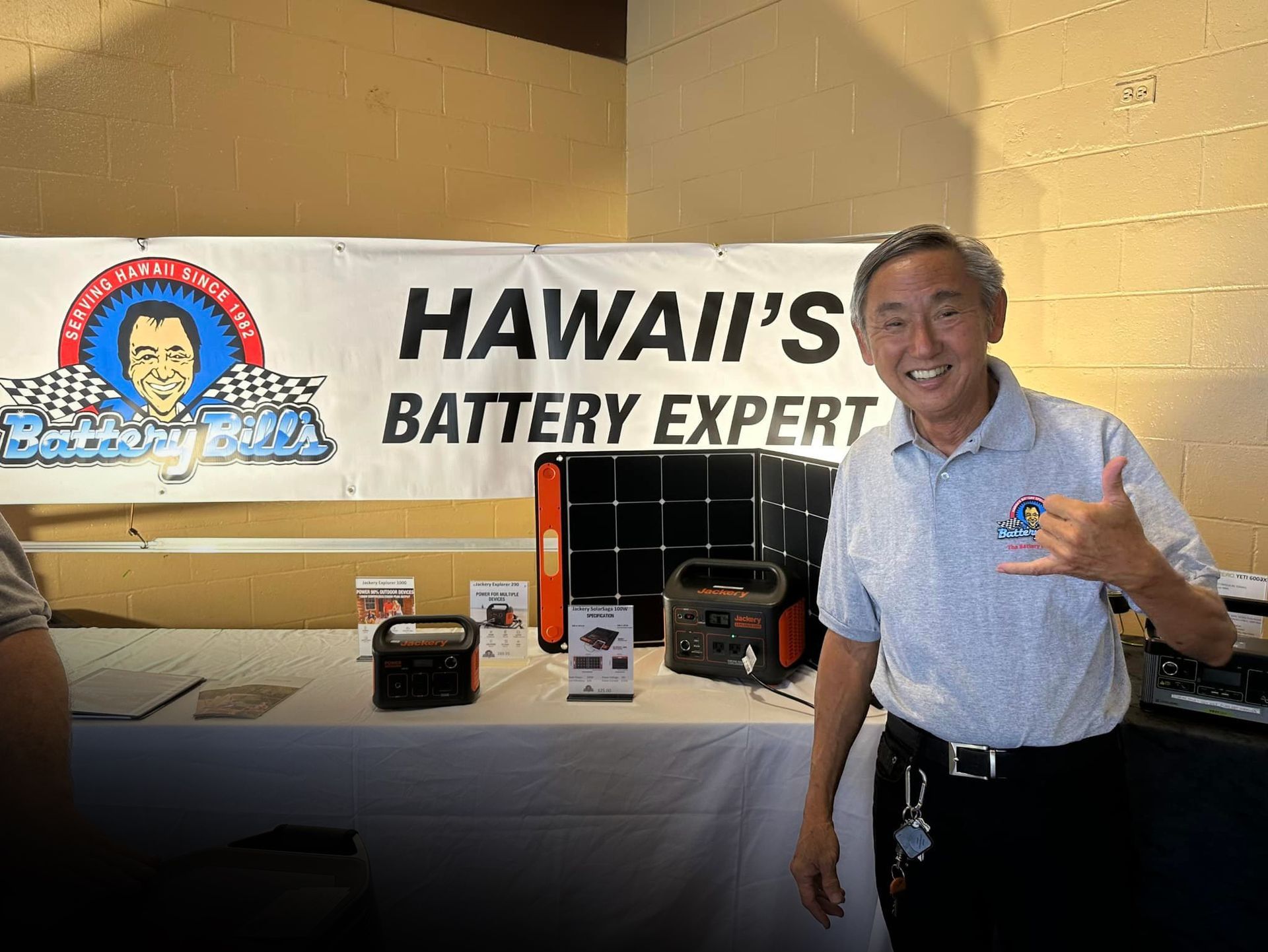 A man is standing in front of a sign that says hawaii 's battery expert