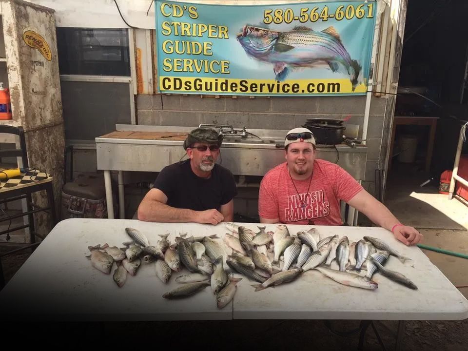 Two men are sitting at a table with a bunch of fish on it