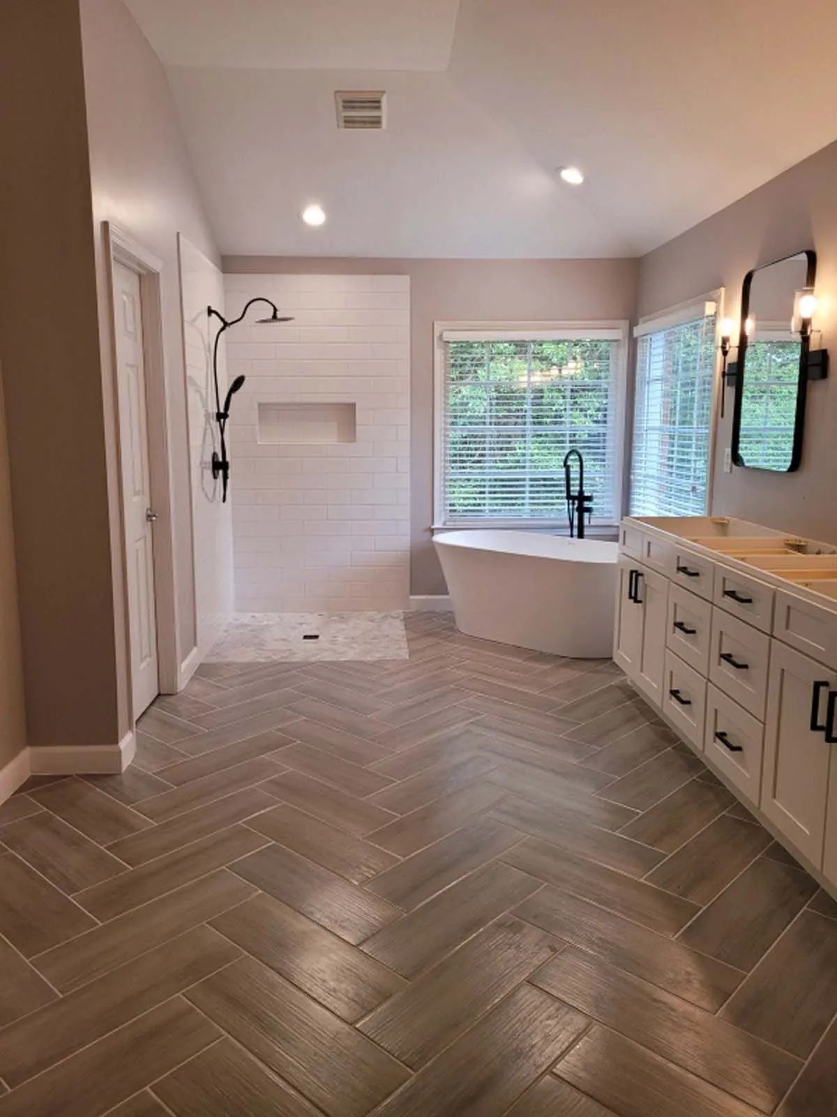 A bathroom with a white freestanding tub, walk-in shower with white shiplap walls, double vanity
