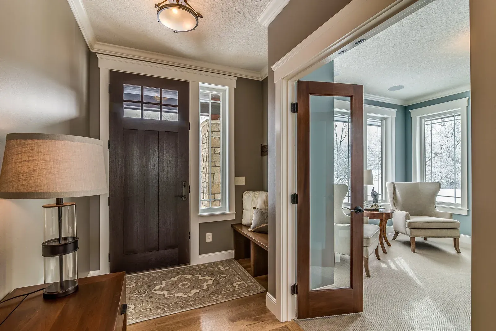 A charcoal-gray front door with five horizontal glass panels, positioned next to a tall, frosted glass sidelight.