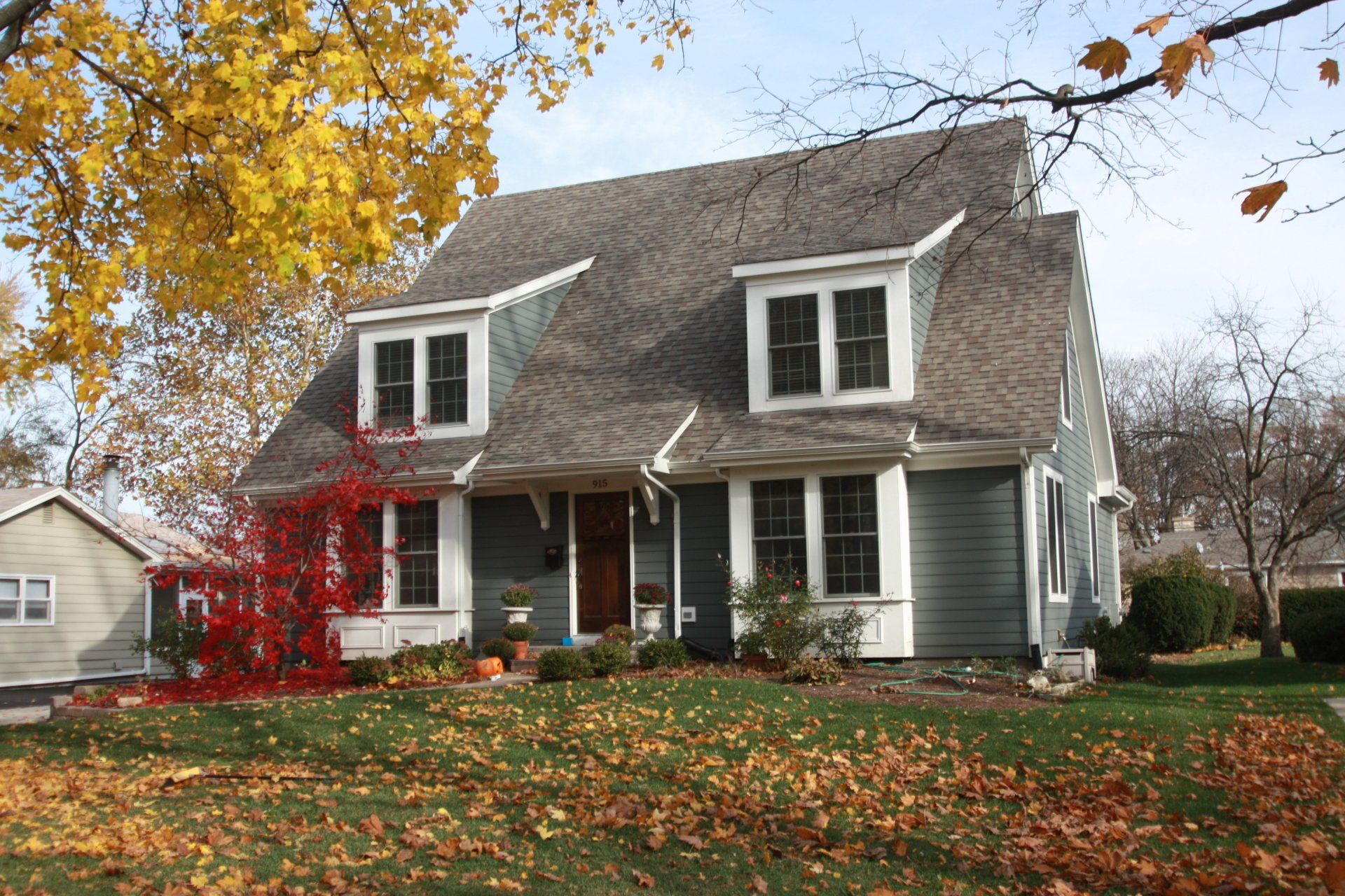 A house with a lot of leaves on the ground in front of it