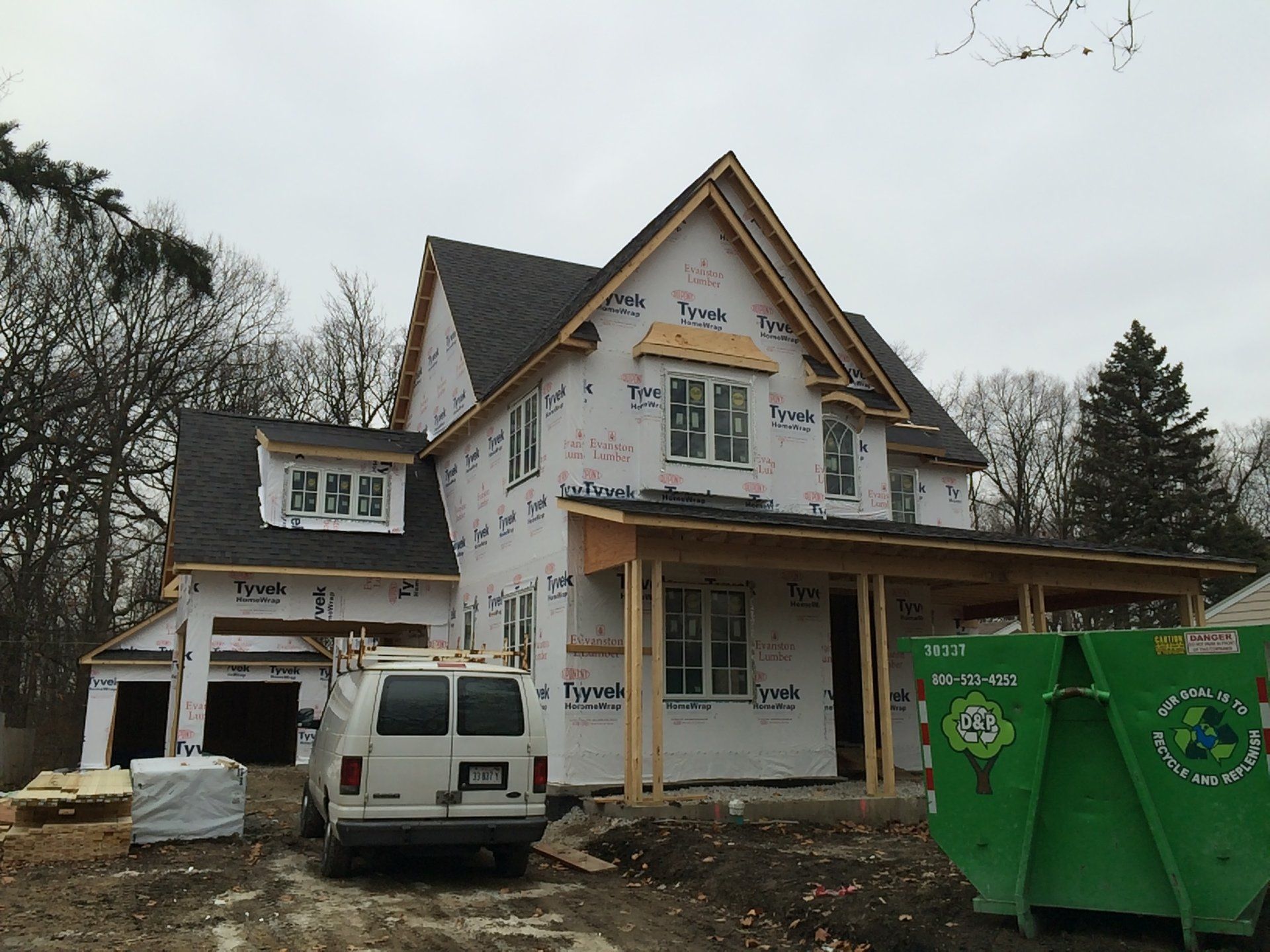 A white van is parked in front of a house under construction