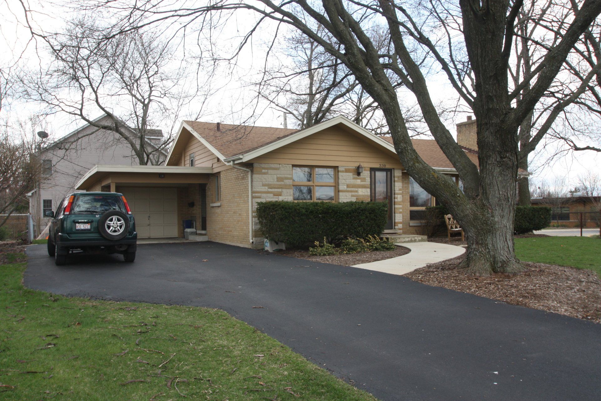 A green suv is parked in front of a house