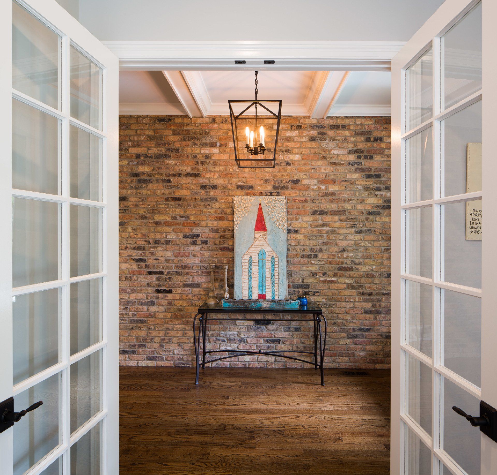 A hallway with a brick wall and a painting on the wall