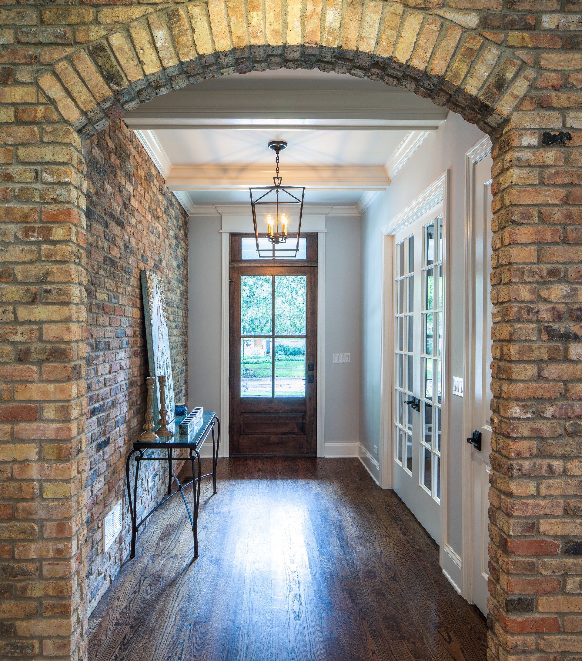 A hallway with a brick wall and a wooden door