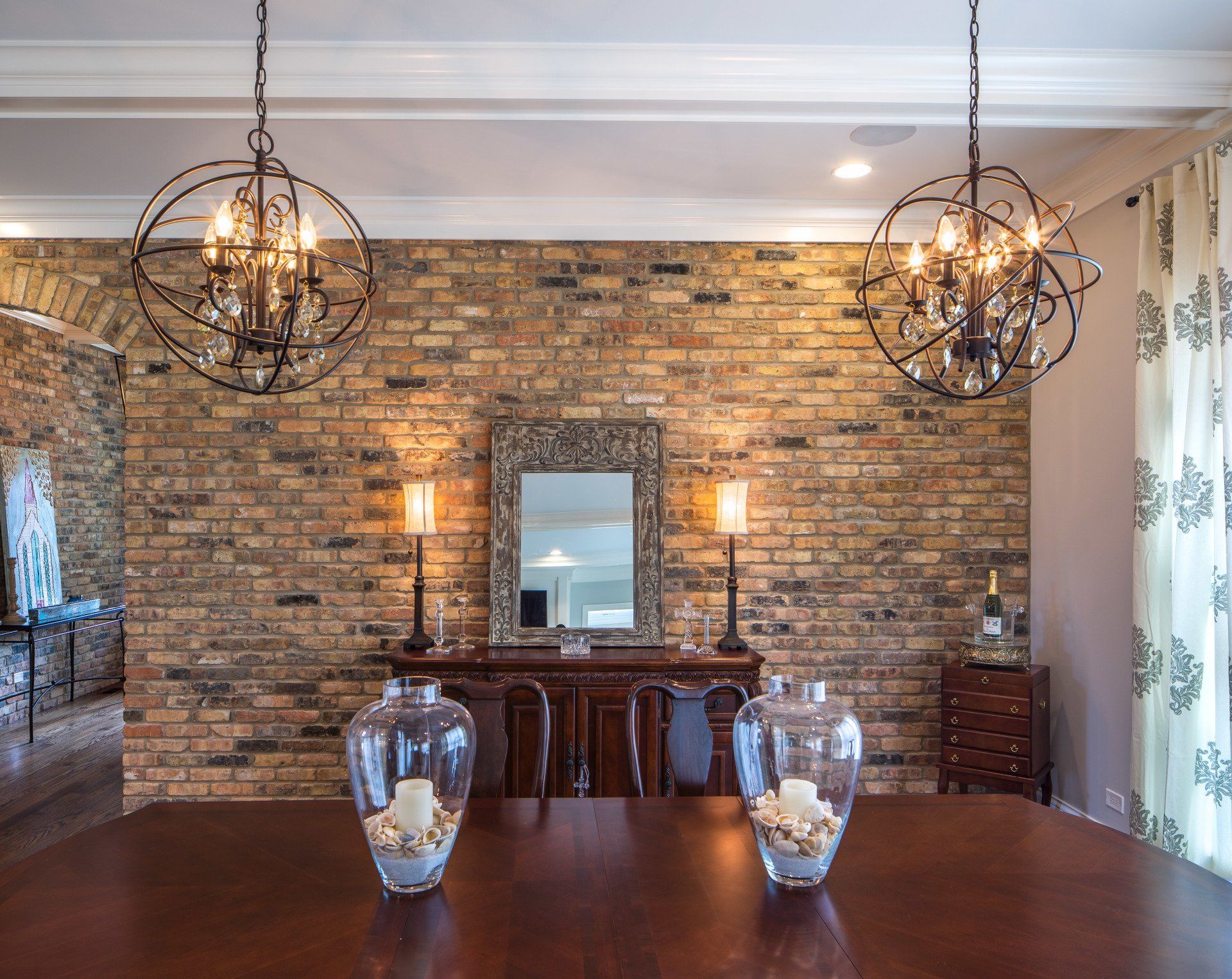 A dining room with a brick wall and two vases on the table