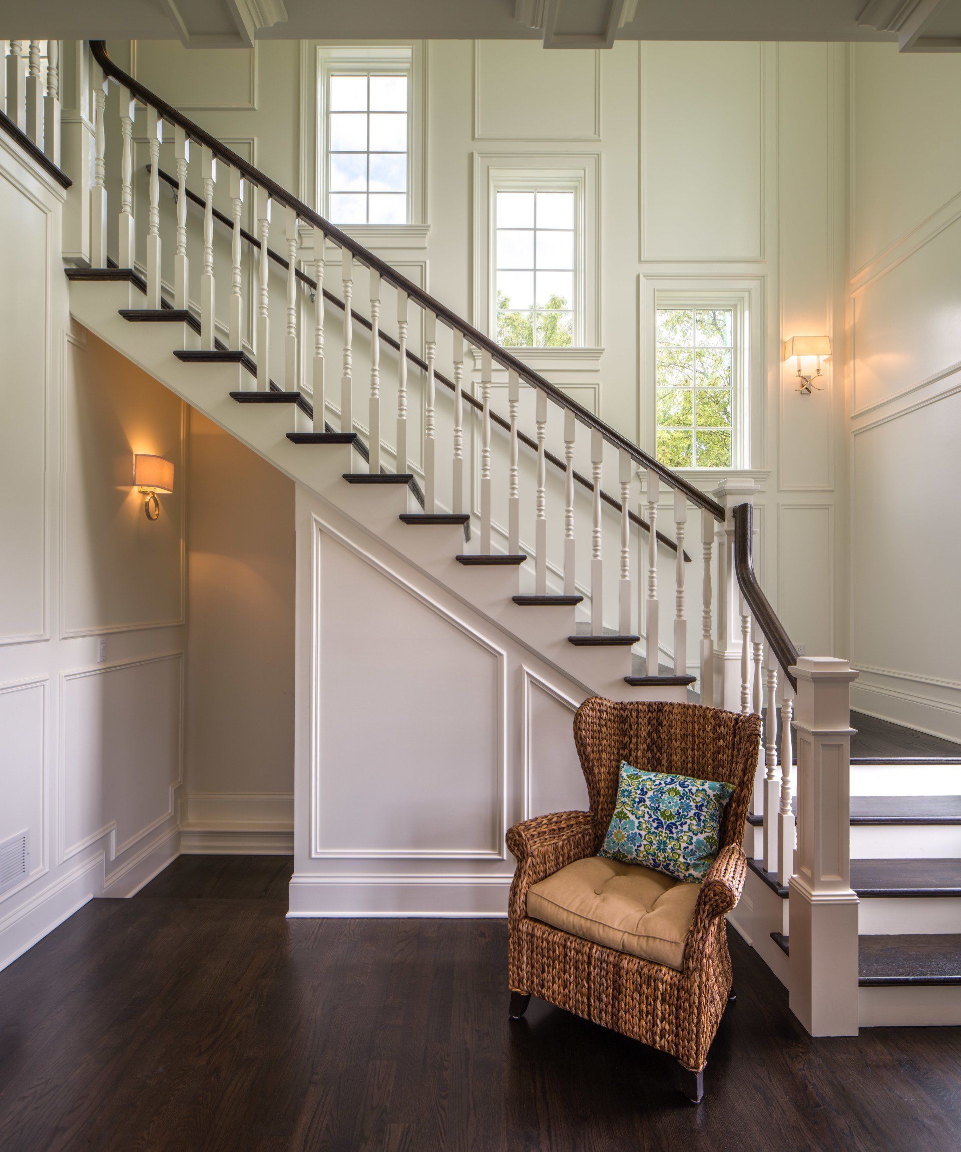 A wicker chair sits in front of a staircase