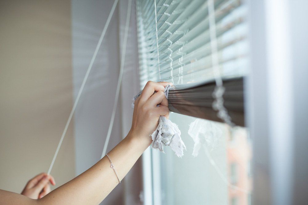 Hand of young woman cleaning blinds by cloth — Blind Cleaning in Tweed Heads, NSW